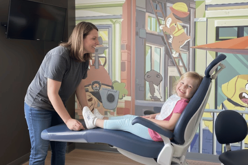 Young girl smiling with mother during dental visit.