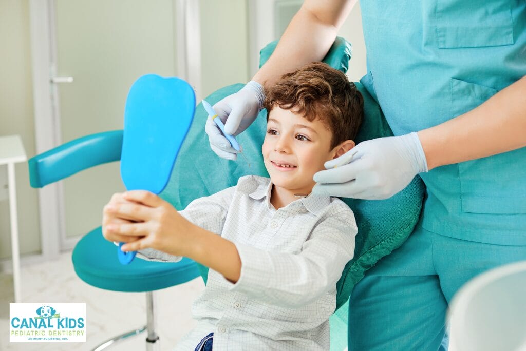 Child holding mirror while pediatric dentist examines teeth